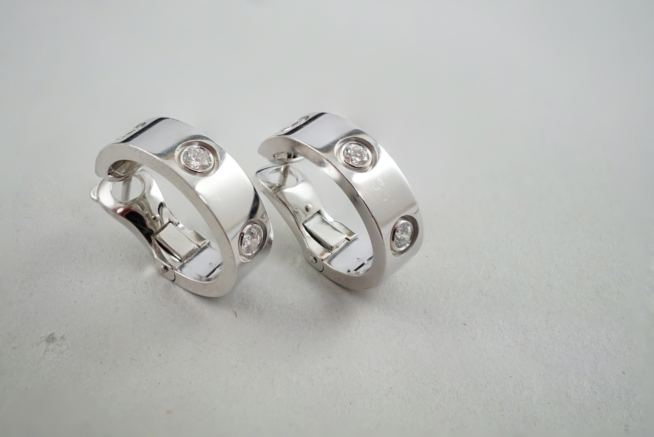 A pair of 2006 Cartier 18ct white gold and three stone round cut diamond set demi-lune earrings